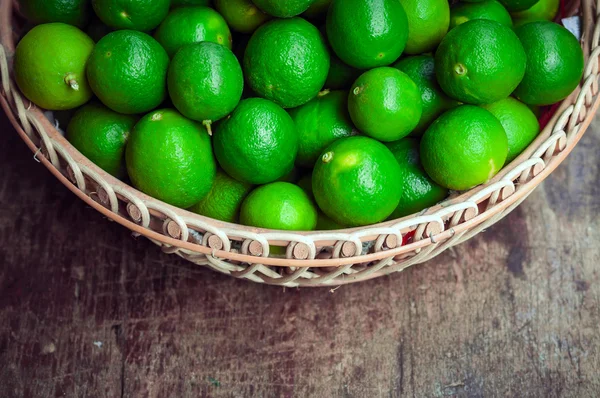 Green lemon in rattan basket — Stock Photo, Image