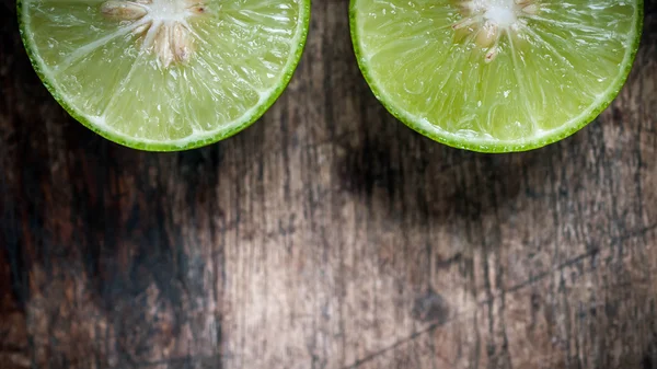 Limão verde corte no fundo de madeira — Fotografia de Stock