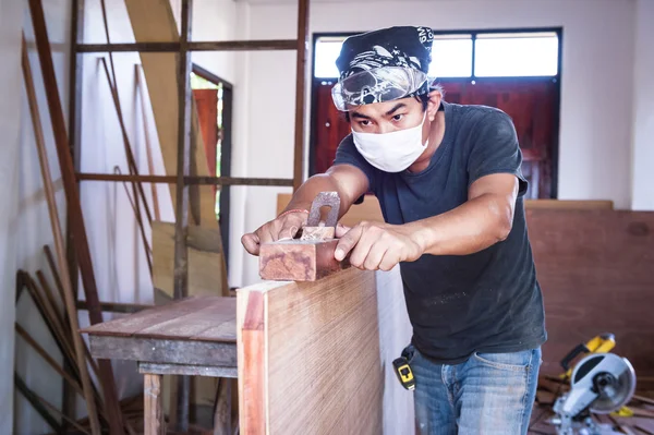 Carpintero hombre tomar una herramienta cepilladora con madera en el taller —  Fotos de Stock