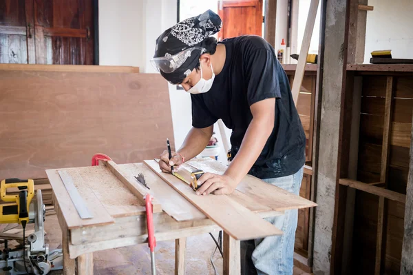 Jeune menuisier travaillant le bois en atelier — Photo
