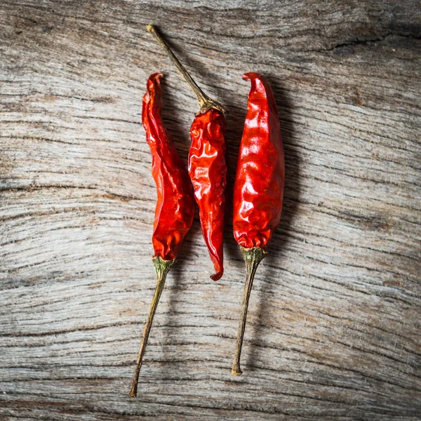 Červené chilli na dřevěné pozadí — Stock fotografie