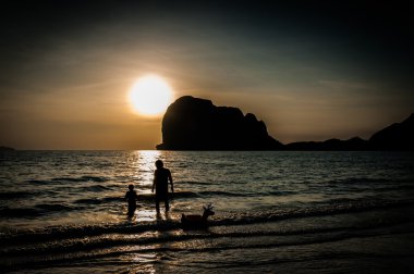 Baba ve oğul, sahilde günbatımı Zamanı