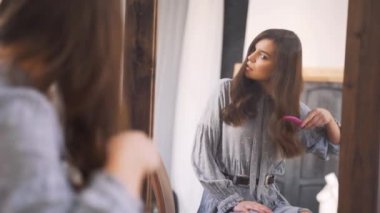 Kafasından vurulmuş, bin yıllık melez bir kadının aynaya bakıp saçlarını taramasını çekmiş. Sinirli genç bir kız. Hasarlı saçtan memnun değil. Tarzı zor, sabah rutini..