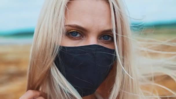 Portrait d'une jeune fille souriante portant un masque noir, en raison de la pandémie de coronavirus et de la pollution de l'environnement. Il regarde la caméra.. — Video