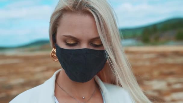 Portret van een lachend, jong meisje met een zwart masker, als gevolg van de coronavirus pandemie en milieuvervuiling. Hij kijkt naar de camera.. — Stockvideo