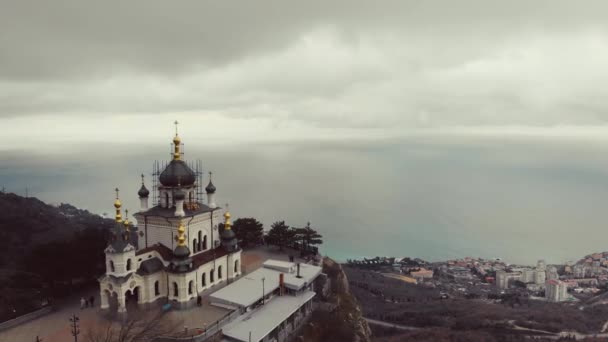 Церква Форос на вершині гори, Форос, Кримський півострів. Лети над сніжно-білою церквою з зеленими куполами на вершині гори, покриті густою зеленню. Християнська церква на скелі над Чорним морем. — стокове відео