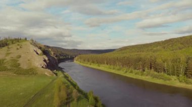 Nehrin havadan görünüşü, Güney Ural, Rusya. Fırtınalı geniş bir koyu renk nehri, sık yemyeşil ağaçları ve alçak çayırları olan yüksek bir tepe arasında akar. Mavi gökyüzünde küçük gri bulutlar hareket ediyor. Yaz