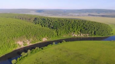 Nehrin havadan görünüşü, Güney Ural, Rusya. Fırtınalı geniş bir koyu renk nehri, sık yemyeşil ağaçları ve alçak çayırları olan yüksek bir tepe arasında akar. Mavi gökyüzünde küçük gri bulutlar hareket ediyor. Yaz