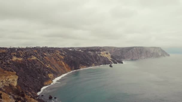 Lucht uitzicht op de golven breken op de rotsen in de Zwarte Zee, Cape Fiolent, de Krim schiereiland. Vliegend op een troon over sterke grote golven die neerstorten op scherpe rotsachtige kliffen. Bewolkte en sombere lucht — Stockvideo