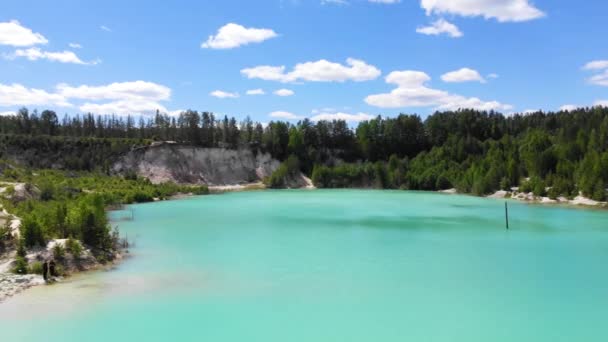 Flygfoto över konstgjord sjö, kaolin dagbrott och turkost vatten. Emerald konstgjord damm. Vita sandstränder, ljusa grönska och stigar på sidorna av dammen. Blå himmel med vita moln, soligt — Stockvideo