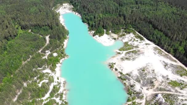 Vista aérea del lago artificial, caolín a cielo abierto y agua turquesa. Estanque artificial esmeralda. Orillas de arena blanca, vegetación brillante y senderos a los lados del estanque. Cielo azul con nubes blancas, soleado — Vídeo de stock