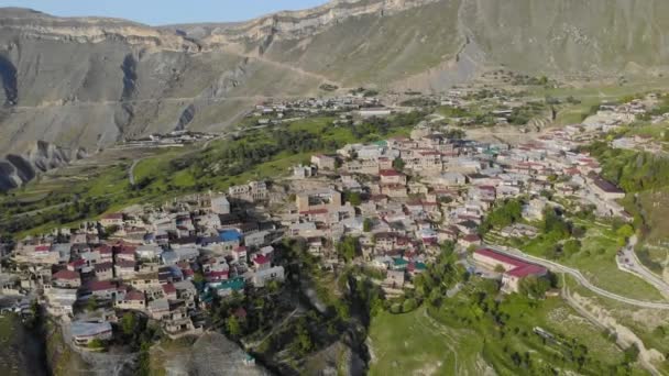 Vista aérea da aldeia de aul no Daguestão. Há muitas casas antigas com telhados coloridos no topo da montanha. Vista incrível das enormes montanhas. Antiga povoação do Cáucaso — Vídeo de Stock