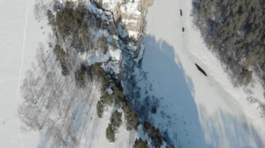 Dağ yamacı ve nehrin havadan görünüşü. Güney Ural, Rusya 'da dondurucu soğuk karlı bir sabah. Geniş nehir donmuş ve buzla kaplı. İnsanlar yüksek kayalıklarda yürüyor