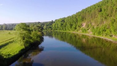 Nehrin havadan görünüşü, Güney Ural, Rusya. Fırtınalı geniş bir koyu renk nehri, sık yemyeşil ağaçları ve alçak çayırları olan yüksek bir tepe arasında akar. Mavi gökyüzünde küçük gri bulutlar hareket ediyor. Yaz