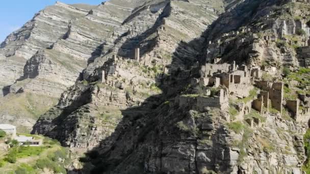 Widok z powietrza na martwą wioskę na szczycie góry. Starożytne budynki, kamienne ruiny starożytnego miasta. Niesamowita, unikalna opuszczona wioska. Kamienne domy opuszczonej wioski Dagestan — Wideo stockowe