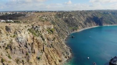 Kayalara çarpan dalgaların havadan görüntüsü. Karadeniz 'in mavi dalgalarının en üst görüntüsü. Dağın tepesindeki kırmızı araba. Gemi su üzerinde yelken açar. Kayalar denizden görülebilir.