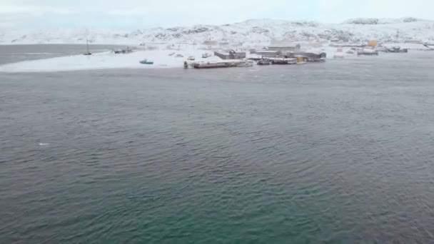 Вид с воздуха на Баренцево море, Атлантический океан, Мурманск. Зима. Поселение на берегу залива. На берегу есть лодки разного цвета. Жизнь людей в Арктическом круге — стоковое видео