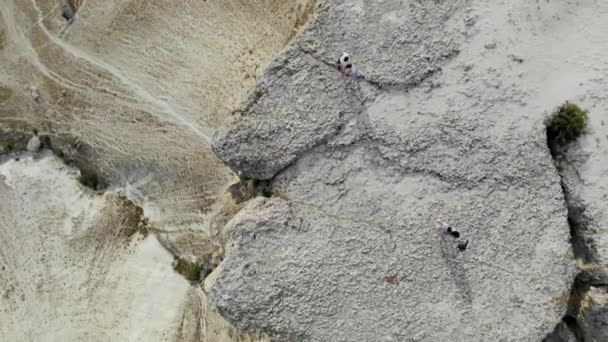 Aerial view of White Rock, Crimean Peninsula. There are cars at the top of the high cliff. Tourists stroll along the rock plateau. Trails run from the bottom of the mountain, fields turn green — Stock Video