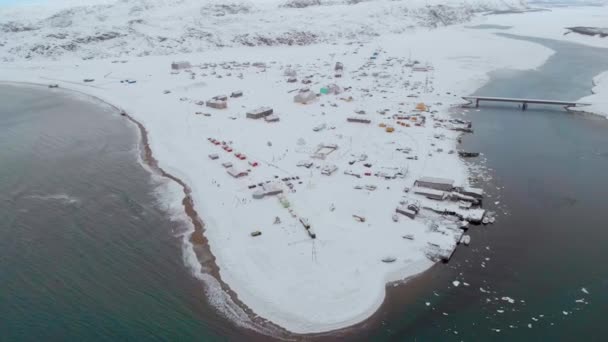 Vista aérea de Barents Sea Bay, Océano Atlántico, Murmansk. El mar azul se rompe en olas blancas en las orillas en las que se encuentran las casas. Tormenta. El suelo está cubierto de nieve. El invierno. Turismo — Vídeo de stock