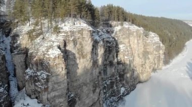 Dağ yamacı ve nehrin havadan görünüşü. Güney Ural, Rusya 'da dondurucu soğuk karlı bir sabah. Geniş nehir donmuş ve buzla kaplı. İnsanlar yüksek kayalıklarda yürüyor