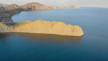 Cape Chameleon ve Quiet Bay, Kırım Yarımadası 'nın hava manzarası. Karadeniz 'in dalgaları pelerinin bej rengi tepenin üzerinde süzülüyor. Sessiz Körfez 'deki pürüzsüz su güneşle aydınlanır. Gün doğumu ya da gün batımı