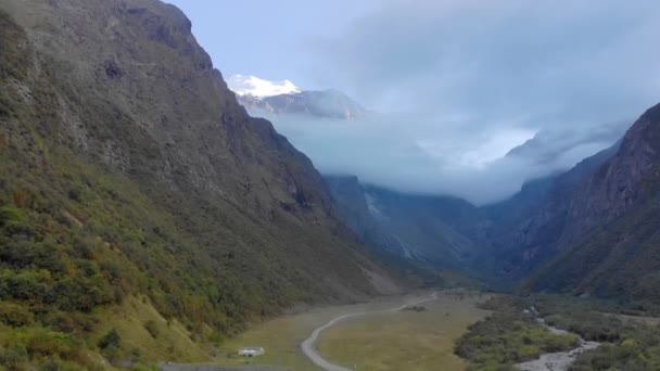 Luchtfoto van bergkloof Lake Ritsa, Abchazië. De pisten zijn bedekt met groen. Er zijn scherpe bergtoppen die zich verbergen in wolken. De weg loopt langs de bergrivier beneden. — Stockvideo