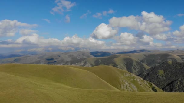 从空中俯瞰穿过Elbrus地区高加索山脊的公路。汽车站在绿色草地中间的路上.游客们欣赏山景.太阳照亮了高山的最高峰 — 图库视频影像