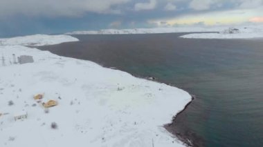 Barents Sea Bay, Atlantik Okyanusu, Murmansk 'ın hava manzarası. Mavi deniz, evlerin bulunduğu kıyılarda beyaz dalgalara ayrılıyor. Fırtına. Zemin karla kaplı. Kış. Turizm