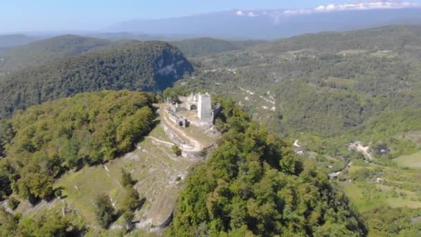 Aerial view of defense tower. The white stone fortress is located on the top of the mountain. It is illuminated by bright sunlight. You can see serpentine road and Caucasian ridge in the distance — Stock Video
