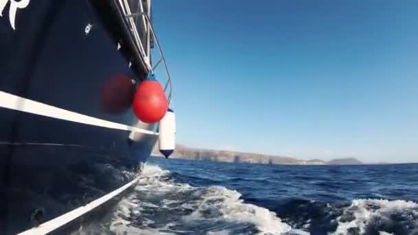 A kék jacht gyorsan vitorlázik a sötét óceán hullámain. Oldalnézet a tengerre vagy az óceánra és a hullámokra. A sós víz habzik. A vízvonal látható a jachtok burkolatán. Vörös-fehér sárvédők vannak a fedélzeten. — Stock videók