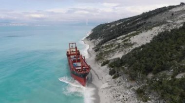 Afrika kargo gemisi Rio 'nun Krasnodar Bölgesi' ndeki hava görüntüsü. Büyük gemi karaya oturdu. Gök mavisi dalgalar, kumlu sahilde hareketsiz duran kırmızı taşıyıcının kenarlarını yıkıyor.