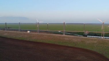Rüzgar türbinlerinin hava görüntüsü. Boş tarlanın arka planında çiftlik rüzgârı türbinleri. Sakin hava ve rüzgar türbinleri hareket olmadan çalışmaz. Rüzgar türbinleri boyunca giden yollar mesafeye çıkıyor.