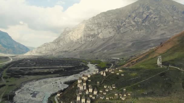 Вид с воздуха на город мертвых, Северная Осетия. Аланские захоронения находятся на холме на Кавказе. Пути между склепами. Ритуальные сооружения в виде белых домов с тёмными крышами. Исторический некрополь — стоковое видео