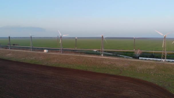 Flygfoto över vindkraftverk. Gård vindkraftverk på bakgrunden av tomt fält. Lugnt väder och vindkraftverk fungerar inte utan rörelse. Vägar längs vindturbinerna går i fjärran — Stockvideo