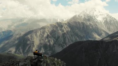 Çift dağın tepesinde, Kafkasya 'da oturuyor. Kafkas dağlarına tepeden bakan bir dağ sırasının kenarında duruyor. Dağların karlı zirveleri. Bulutlar yukarıdan sarkıyor. Korkunç güzellik.