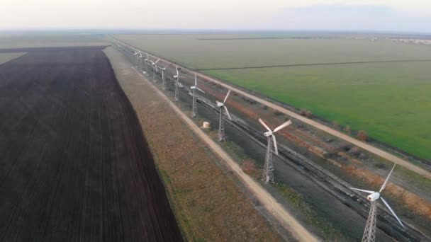 風力タービンの空中ビュー。空のフィールドを背景にファーム風力タービン。穏やかな天候と風力タービンは動きなしでは動作しません。風力タービンに沿った経路は距離に入ります — ストック動画