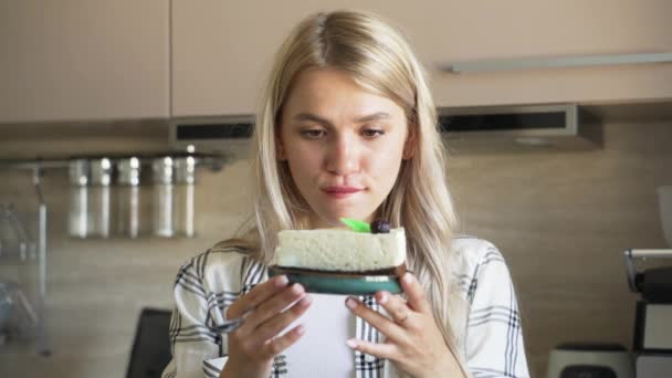 A mulher hesita em comer o bolo ou não. a menina segue uma dieta saudável, mas ela realmente quer experimentar o bolo — Vídeo de Stock