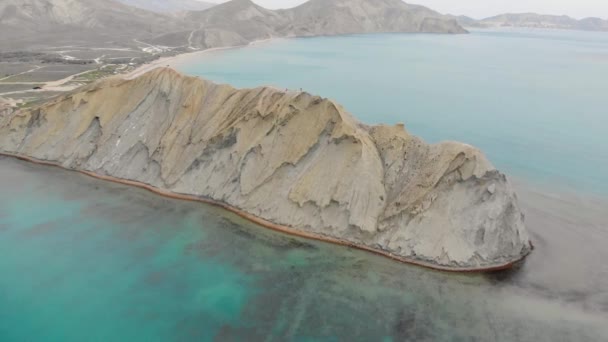 Vista aérea del Cabo Camaleón y Bahía Tranquilo, Península de Crimea. Las olas del Mar Negro se lavan sobre la colina beige del cabo. El agua lisa en la bahía tranquila está iluminada por el sol. Salida o puesta del sol — Vídeo de stock