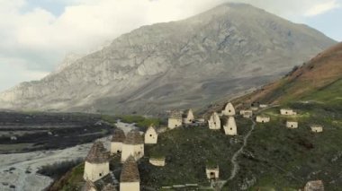 Ölülerin şehri, Kuzey Osetya 'nın havadan görünüşü. Alanlı cenazeler Kafkasya 'daki tepede bulunur. Mahzenler arasındaki yollar. Beyaz evler ve karanlık çatılar şeklinde ayinsel yapılar. Tarihsel nekropolis