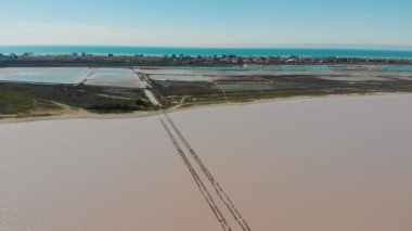 Pembe ıssız tuz gölü, Kırım Yarımadası 'nın havadan görünüşü. Uzakta, tahta kütüklerden oluşan bir patika suya giriyor. Göl ve deniz kumlu bir şeritle ayrılır. Eşsiz doğa.