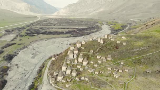 Luchtfoto van dode stad, Noord-Ossetië. Alanian begrafenissen bevinden zich op heuvel in de Kaukasus. Paden tussen crypten. Rituele structuren in de vorm van witte huizen met donkere daken. Historische necropolis — Stockvideo