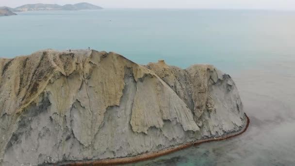 Vista aérea del Cabo Camaleón y Bahía Tranquilo, Península de Crimea. Las olas del Mar Negro se lavan sobre la colina beige del cabo. El agua lisa en la bahía tranquila está iluminada por el sol. Salida o puesta del sol — Vídeo de stock