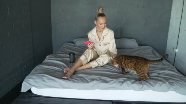 Kobieta w łóżku bawi się z kotem — Wideo stockowe