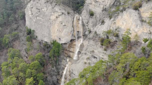 Luchtfoto van de waterval. Bergrivier stroomt naar beneden vanaf de top van grijze rotsen. Witte krachtige waterstralen breken op verschillende rotsniveaus. Er staat een beeld van een adelaar op de richel. Luchtvideoshooting — Stockvideo