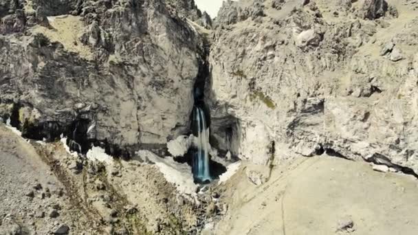 Flygfoto över fjällvattenfall, Elbrus region. Stormiga floden rinner ner från toppen av berget. Strömmen går sönder på marken. Du kan se höga toppar av Kaukasus bergen som är täckta med snö — Stockvideo