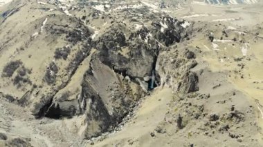 Elbrus bölgesindeki dağ şelalesinin havadan görünüşü. Fırtınalı nehir dağın tepesinden aşağı akıyor. Nehir yerde kırılır. Kafkas dağlarının yüksek tepelerini görebilirsiniz. Karla kaplı.