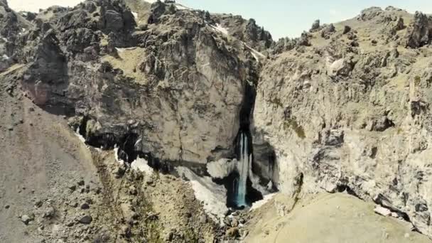 Luftaufnahme des Bergwasserfalls, Elbrus-Region. Stürmischer Fluss fließt vom Gipfel des Berges herunter. Am Boden bricht der Strom ab. Sie können hohe Gipfel des Kaukasus-Gebirges sehen, die mit Schnee bedeckt sind — Stockvideo