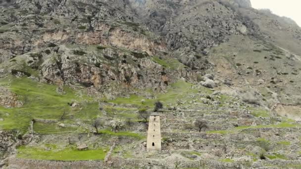 Vista aérea de antiguas torres defensivas. Las fortificaciones se encuentran en laderas de rocas. Los picos de nieve de las montañas y las nubes son visibles en la distancia. Murallas de la antigua ciudad destruida se observan — Vídeo de stock