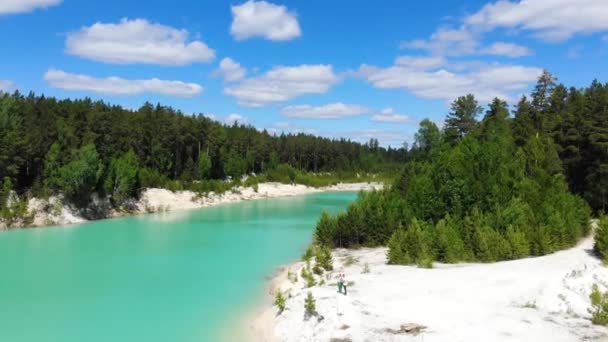 Flygfoto över konstgjord sjö, kaolin dagbrott och turkost vatten. Emerald konstgjord damm. Vita sandstränder, ljusa grönska och stigar på sidorna av dammen. Blå himmel med vita moln, soligt — Stockvideo