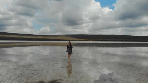 Légi kilátás bézs só tó. A ruhás nő úgy sétál a vízen, mint egy tükörben. A tó vize visszatükrözi a kék eget és a lebegő felhőket. Egyedülálló természet. Elhagyatott — Stock videók